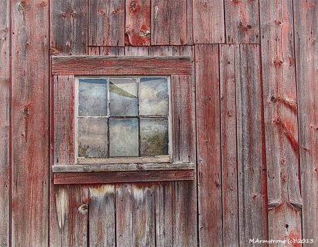 A small window in the wall of an old barn
